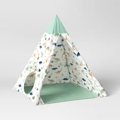 a teepee tent with dinosaurs on it and a green mat in front of it