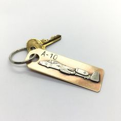 This key chain depicts the A-10 "Warthog" fighter aircraft.  It is hand made from brass and nickel by me in my shop.  The pieces are cut out by hand with a jewelers saw, soldered together, and detailed with various small tools.  The key chain measures 3" long and 1" wide, and comes with a 1" split ring to hold your keys.It will come shipped in a brown paper gift box. Grim Reaper Scythe, Jewelers Saw, A 10 Warthog, Small Tools, Paper Gift Box, Brown Paper, Split Ring, Chains For Men, Paper Gifts