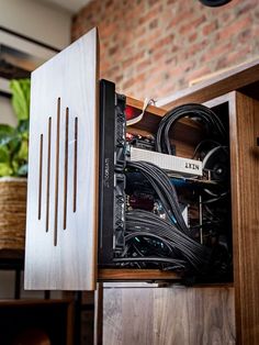 the inside of a computer case with wires and cables in it, sitting on top of a wooden cabinet