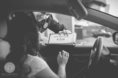 a woman sitting in the driver's seat of a car holding a box with a baby on it