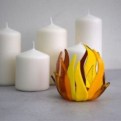 three white candles are sitting next to each other with orange and yellow designs on them