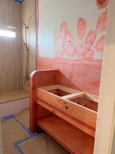 an unfinished bathroom with pink paint on the walls and wood furniture in the foreground