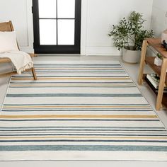 a living room with white walls and striped rug on the floor next to a chair