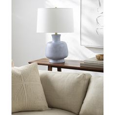 a blue vase sitting on top of a table next to a white lampshade