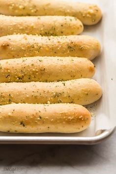 breadsticks lined up in a baking pan with seasoning on the top and bottom