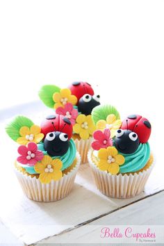 three cupcakes decorated with flowers and ladybugs