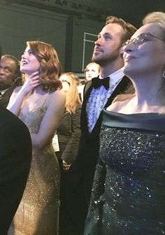 several people in formal wear standing together at an event with one woman looking up to the sky