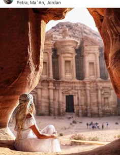 a woman sitting on the ground in front of a building