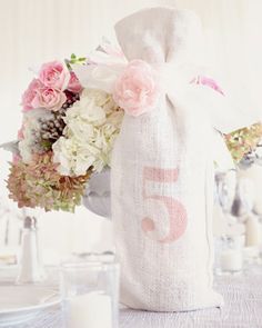 a white bag filled with flowers sitting on top of a table next to a candle