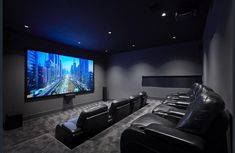 a home theater with two recliners and a large screen on the wall in front of it