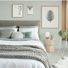 a bed with white sheets and pillows in a bedroom next to two pictures on the wall