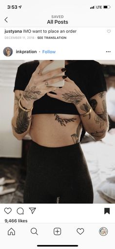 a woman with tattoos on her stomach looking at her cell phone while wearing tight black leggings