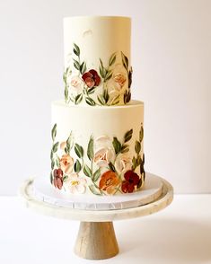 a three tiered cake with flowers painted on it