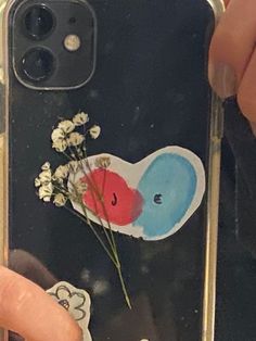 someone holding up their phone case with an elephant and flower sticker on the back