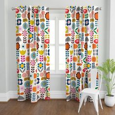 a white chair sitting in front of a window covered in colorful flowers and circles on it