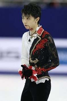 a man in black and white outfit skating on ice with his hands behind his back