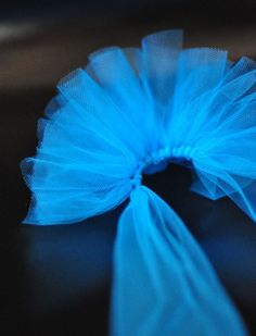 a close up of a blue tulle on a black table with a white object in the background