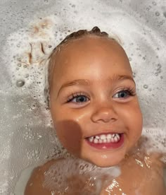 a young child smiles as he takes a bath