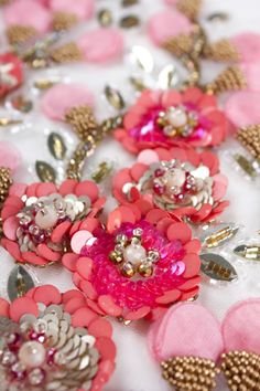 pink and silver flowers on white fabric with sequins in the center, closeup