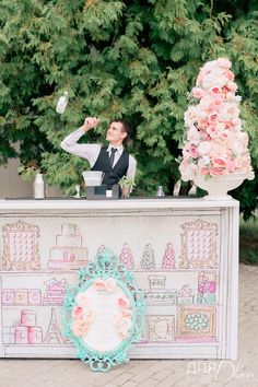 a man in a suit standing at a counter with flowers on it and an ice cream parlor behind him