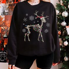 Celebrate the holidays with a quirky gothic edge! This unique sweatshirt features a skeleton reindeer wrapped in festive lights and a Santa hat, bringing spooky cheer to your holiday season. Perfect for fans of dark humor and holiday fun, this cozy unisex design is great for group gatherings, holiday parties, or matching with friends and family. Stand out this season with a little skeletal charm! Available in plus sizes--grab yours today! All of our sweatshirts are custom made to order ► ITEM DETAILS: * Classic unisex crewneck sweatshirt * Ribbed knit collar with seam - Ribbed knit makes the collar highly elastic and helps retain its shape * Fabric blends: medium-heavy fabric blend of 50% cotton and 50% polyester * Fabric blends: Heather Sport colors - 60% polyester, 40% cotton * Double-ne Winter Long Sleeve Sweater With Skull Print, Goth Christmas Sweater, Emo Christmas, Cute Christmas Sweaters, Gothic Holiday, Skeleton Christmas, Goth Christmas, Cute Christmas Sweater, Unique Sweatshirt