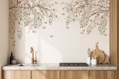 a kitchen wall with flowers and butterflies painted on the walls, along with wooden cabinets