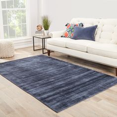 a living room with white couches and blue rugs on the wooden flooring