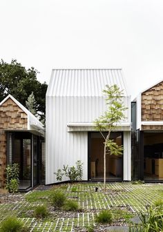 the house is made out of wood and has white shingles on the roof, along with brick walkways