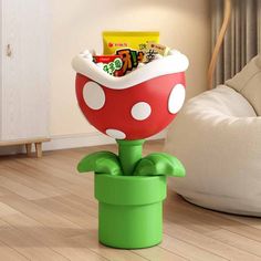 a mushroom shaped container with snacks in it on top of a green planter next to a white couch