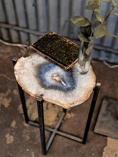 a small table with a flower in a vase on it and a piece of wood sitting on top of it