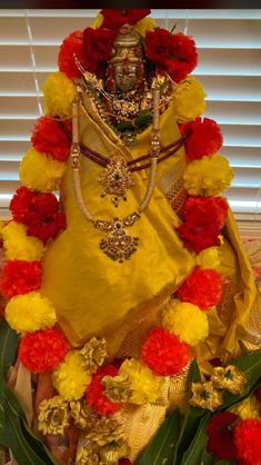 the statue is dressed in yellow and red flowers