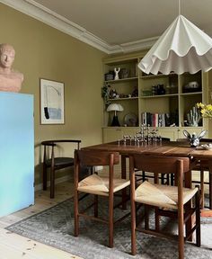 a dining room table with chairs and an umbrella over it in front of a bookshelf