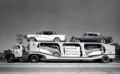 three cars are on the back of a truck that is parked in front of another car