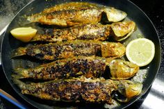 grilled fish and lemons in a pan on the stove