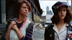 two women standing next to each other on a city street