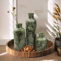 three green vases sitting on top of a wooden tray