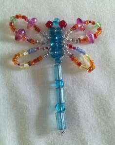 a dragonfly made out of glass beads on a white cloth with beading around it