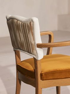 a wooden chair with a yellow cushion on it's back and armrests