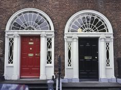 two red doors are on the side of a brick building with white trim and arched windows