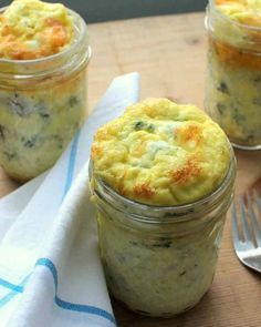 three small jars filled with food on top of a wooden table next to a fork