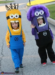 two children in costumes walking down the street with their mouths open and eyes wide open