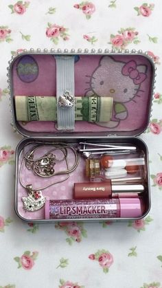 an open hello kitty tin with various items in it on a floral tablecloth background