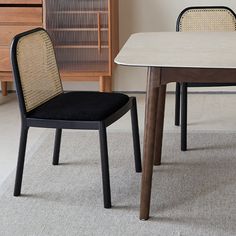 two chairs sitting next to each other in front of a white table with black seats