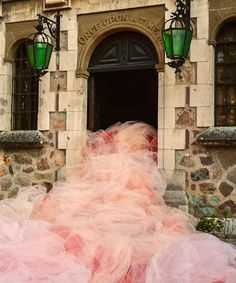 a woman in a pink dress is walking by a building with green lanterns on it