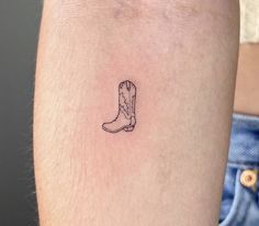 a small cowboy boot tattoo on the right arm and leg, with an outline in the middle