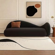 a black and white couch sitting in a living room next to a painting on the wall