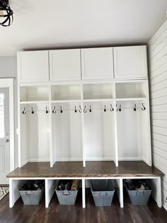 a white mudroom with several storage bins and baskets