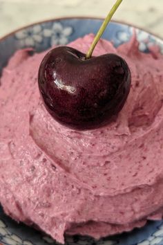 a bowl filled with pink hummus and a cherry on top, ready to be eaten