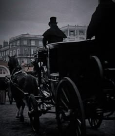 a man riding in a horse drawn carriage down a street next to other horses and carriages