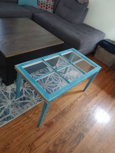 a living room with a couch, coffee table and blue glass side table in it